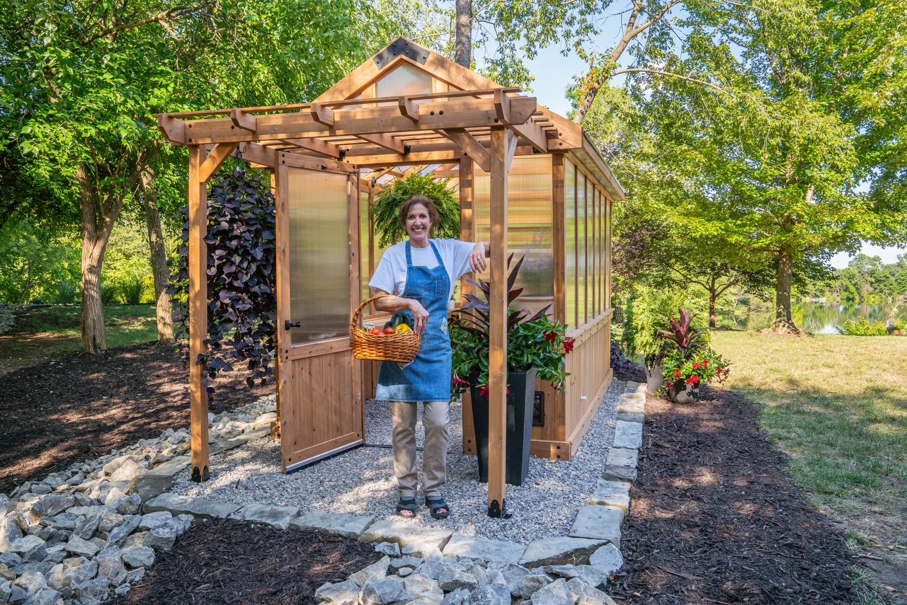 Woman with a basket at the entrance of a Backyard Discovery greenhouse.