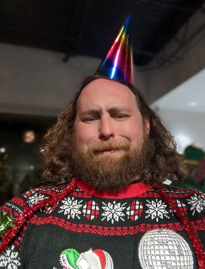 Limelight Team Member: James Mulvenon in a party hat and a dino Christmas sweater on