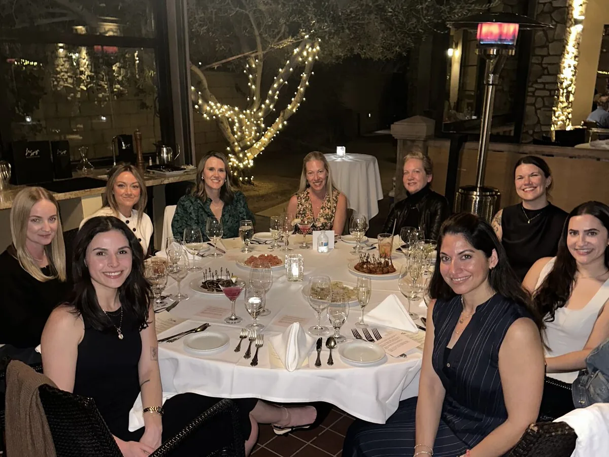 Guests around a candlelit table on a restaurant patio at a Women in Ecommerce dinner